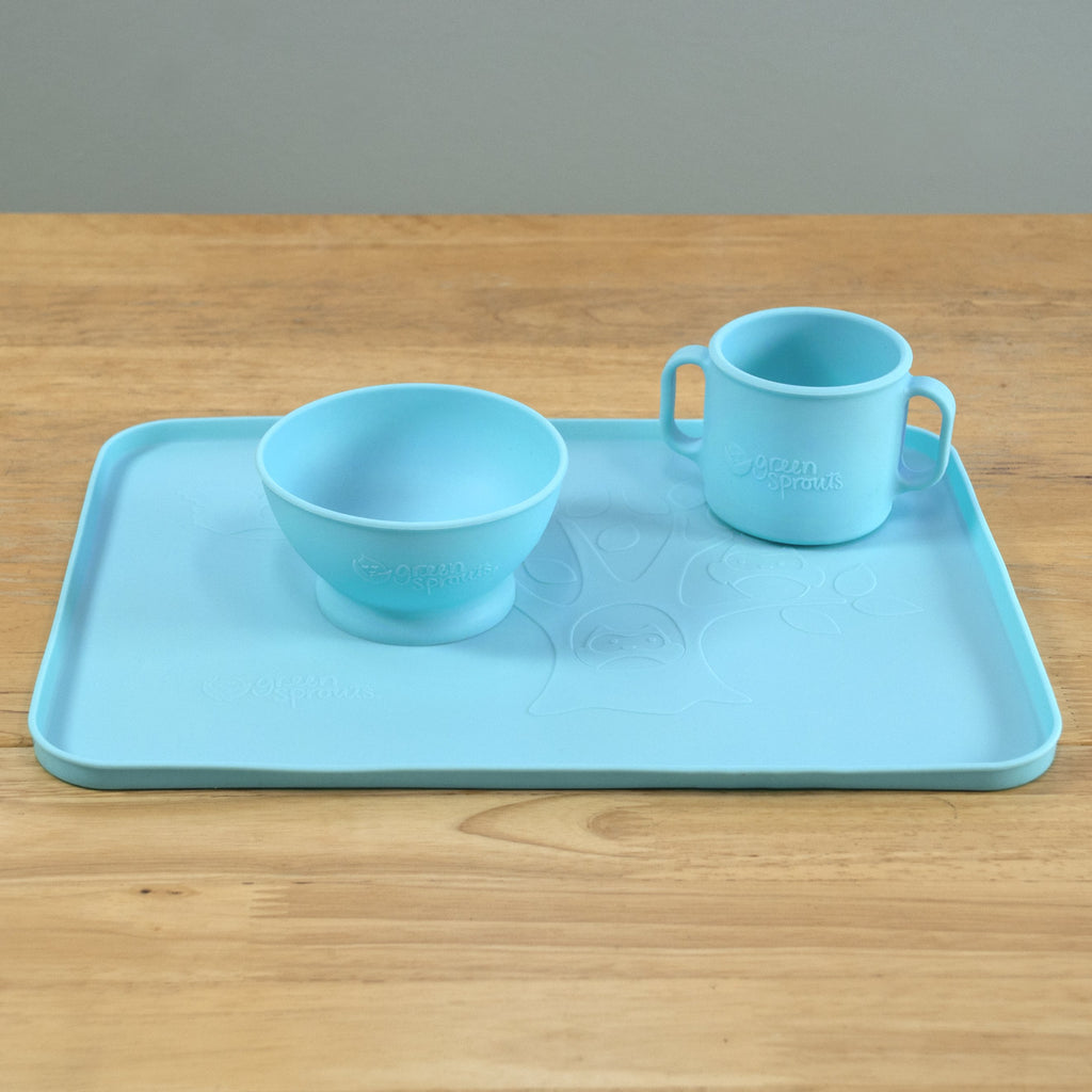 An Aqua Feeding Bowl made from Silicone with a matching aqua cup and platemat on a wooden table
