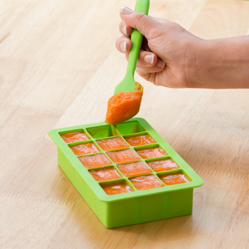 A beautiful carrot puree being put into the green Fresh Baby Food Freezer Tray.