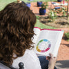 A woman reading the Grow Healthy. Grow Happy. The Whole Baby Guide in her backyard.