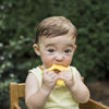 A little baby holding a yellow Cleaning Teether made from Silicone in her mouth.