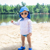 A little boy hanging out on a beach lake while wearing sunglasses and a white Breathable Sun Protection Shirt.
