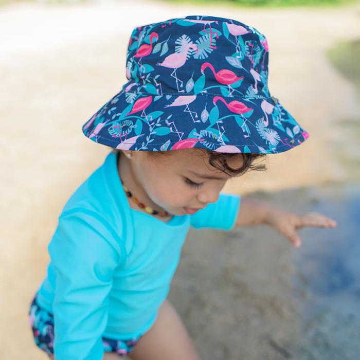 A focused camera shot of the navy flamingo Bucket Sun Protection Hat on dark curly haired girl wearing an aqua shirt.